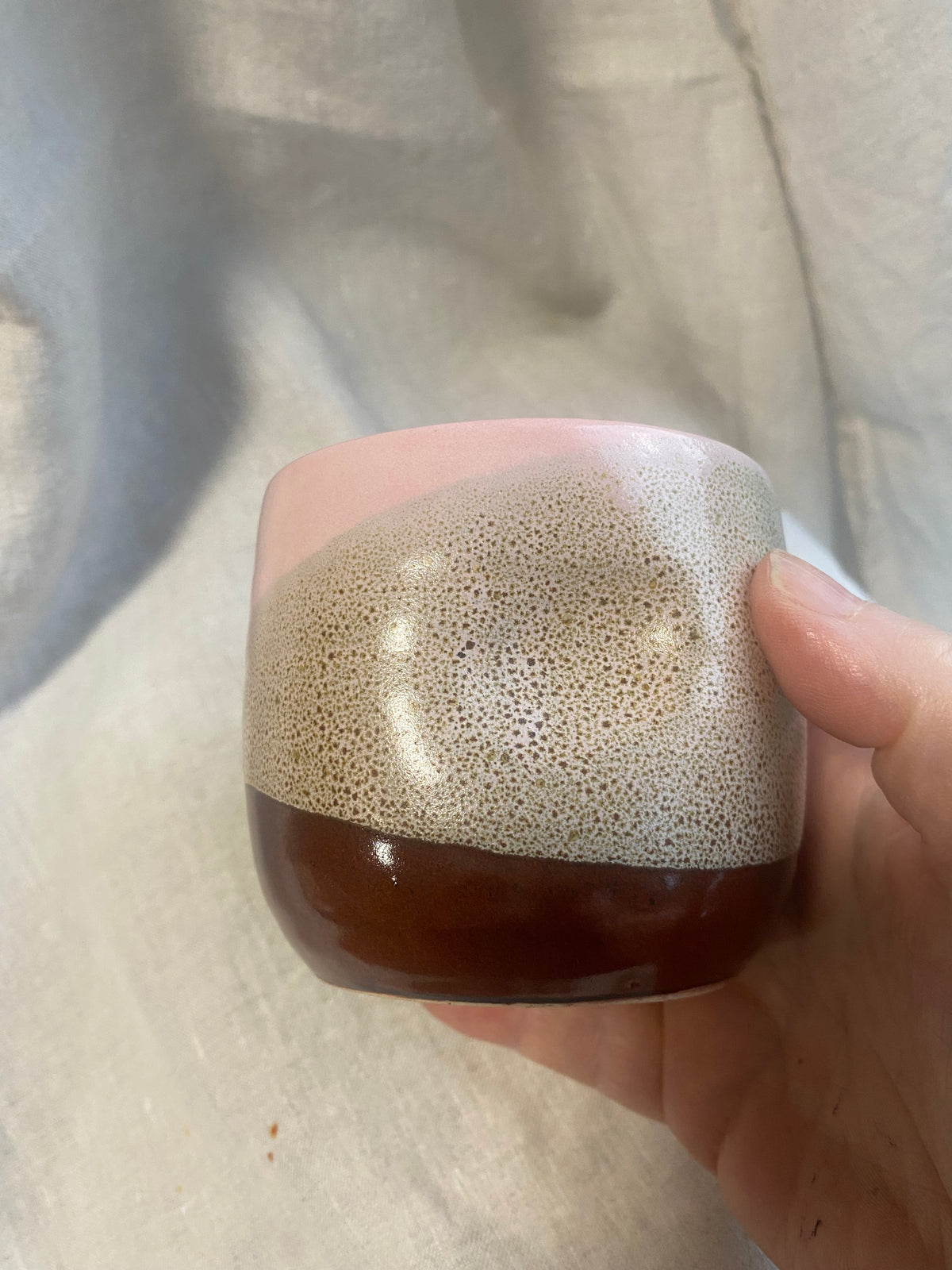 A hand holding cup in pink, brown and bubble effect evocative of hot chocolates and marshmallow